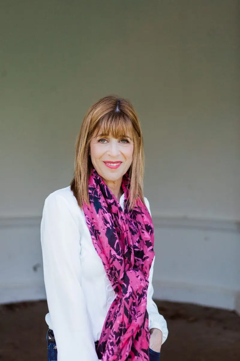 Portrait of Dr Annie Kaszina in a white blouse and pink scarf, smiling warmly