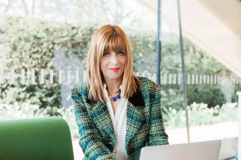 Dr Annie Kaszina working thoughtfully at a laptop in a bright garden room