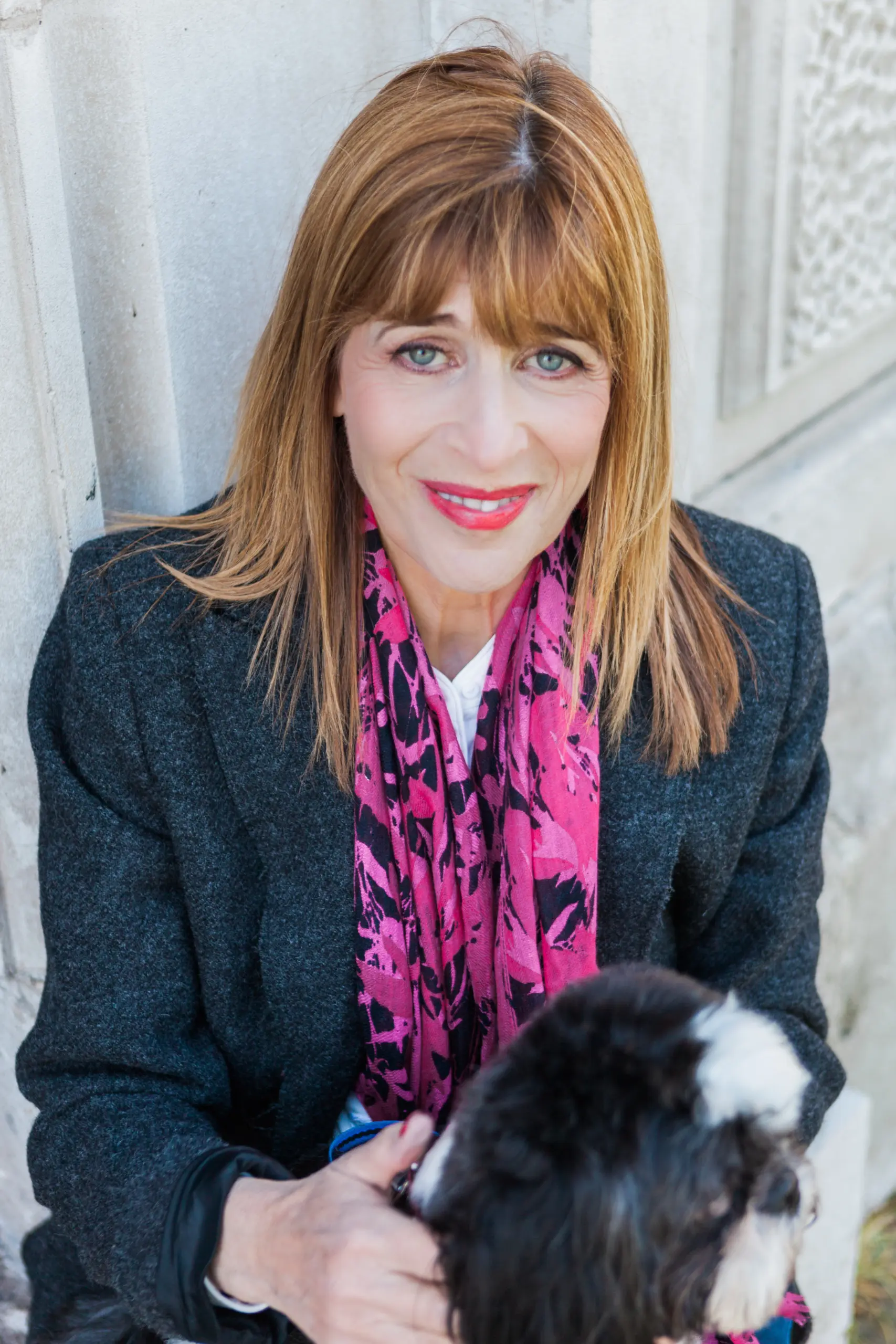 Dr Annie Kaszina seated outdoors with her small dog, smiling warmly at the camera